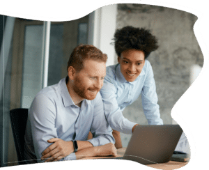 A woman showing something on a screen to a smiling coworker, expressing collaboration, support, and shared success.
