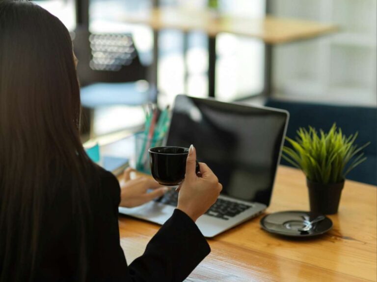 Person sitting at a desk with a laptop and coffee cup, symbolizing occupational therapy support for workplace routines and productivity.