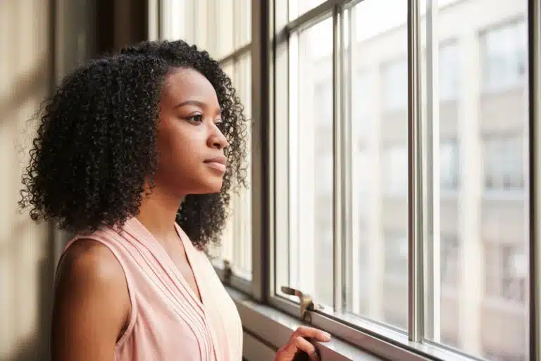 Person looking out a window in Portland reflecting on connection – therapy for loneliness Portland