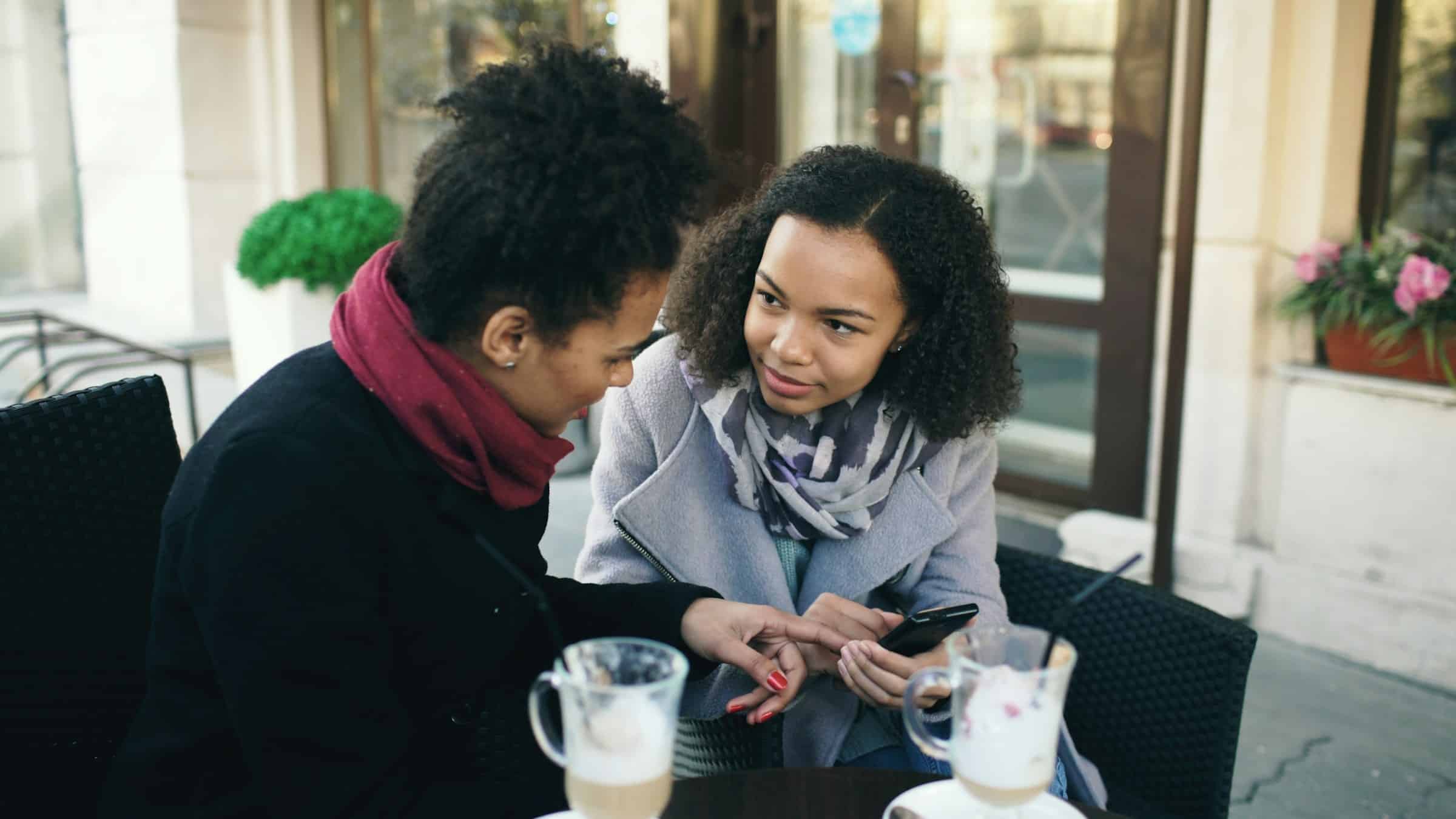 Adults connecting at a café, symbolizing support and community for queer and neurodivergent people