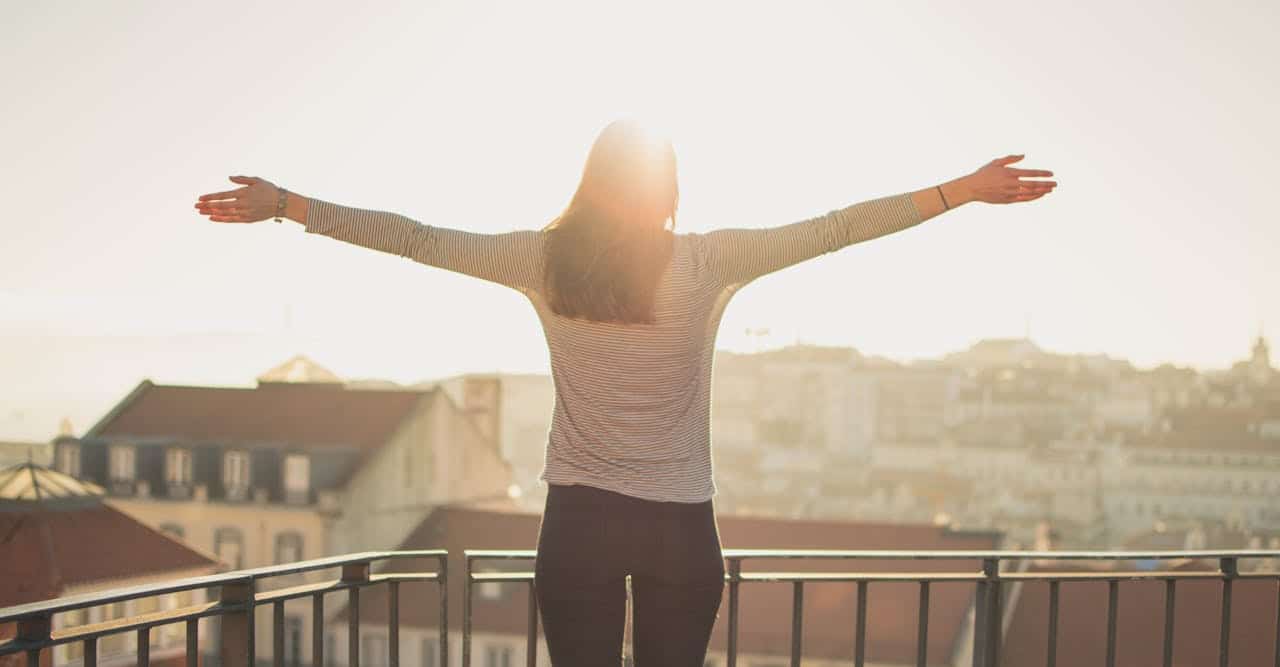 Woman standing with open arms in sunlight representing hope and recovery from depression