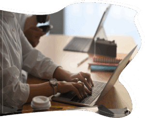 Close view of hands typing on a laptop near a workspace, an everyday scene suggesting research and engagement