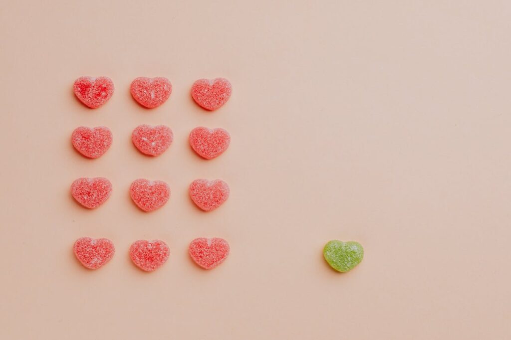 Heart-shaped candies arranged in a pattern with one different color, symbolizing neurodiversity and how ADHD brains differ