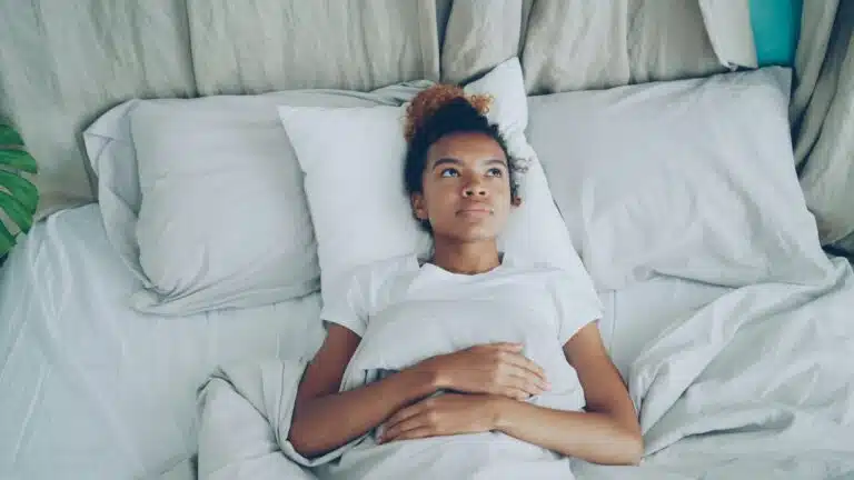 Low motivation therapy morning scene of woman lying awake in bed before beginning daily routine for OT for depression