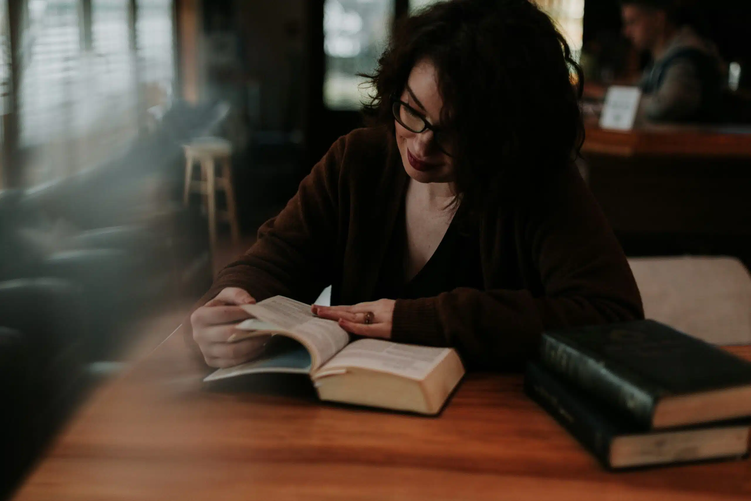 Adult sitting at a table reviewing a book and notes in a calm, low-stimulation environment, reflecting a quiet daily routine with chronic illness.