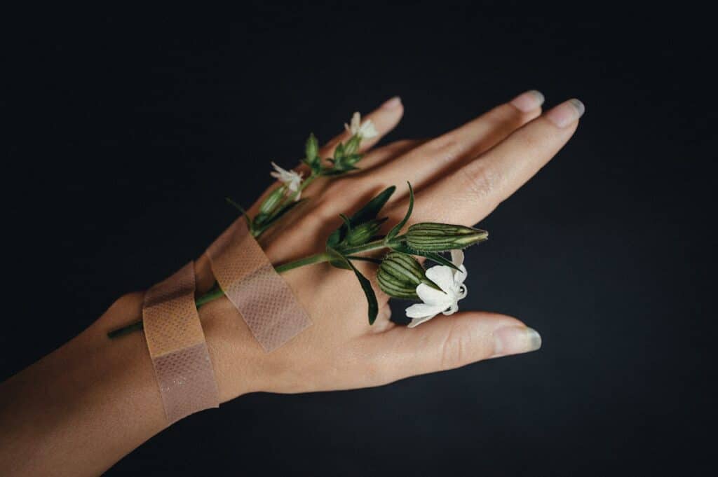 Hand with bandage and flowers representing healing from chronic illness and emotional recovery
