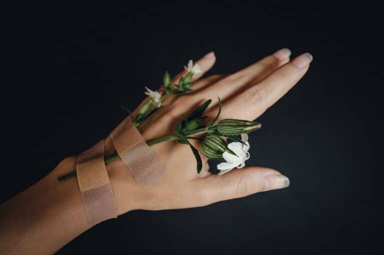 Hand with bandage and flowers representing healing from chronic illness and emotional recovery
