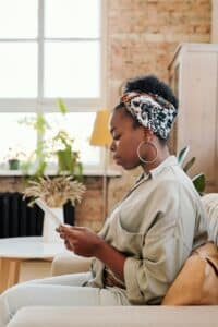 An African American woman reading her phone thoughtfully, reflecting attention, daily demands, and quiet awareness.