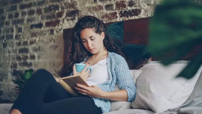 Young adult sitting on a bed using a phone during brain fog therapy and concussion recovery support