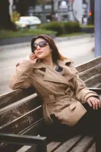A stylish woman showcasing urban winter street wear and classic outerwear while relaxing on a city bench.