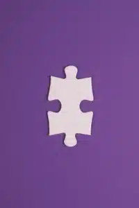 A standalone white jigsaw puzzle piece over a purple surface.