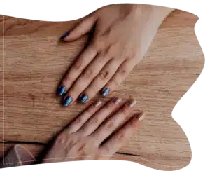 Top-down view of two hands showing blue and nude manicured nails on a wooden background.